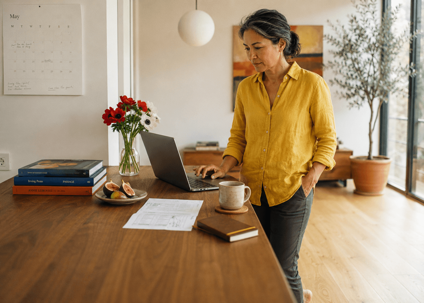 Een vrouw bekijkt haar laptop aan de keukentafel in het ochtendlicht